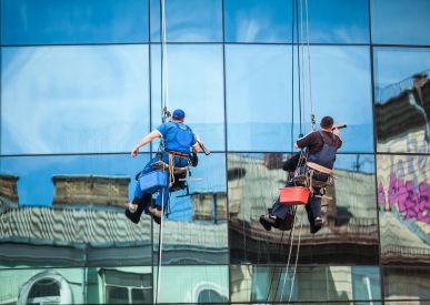 Two rope access technicians cleaning a glass facade